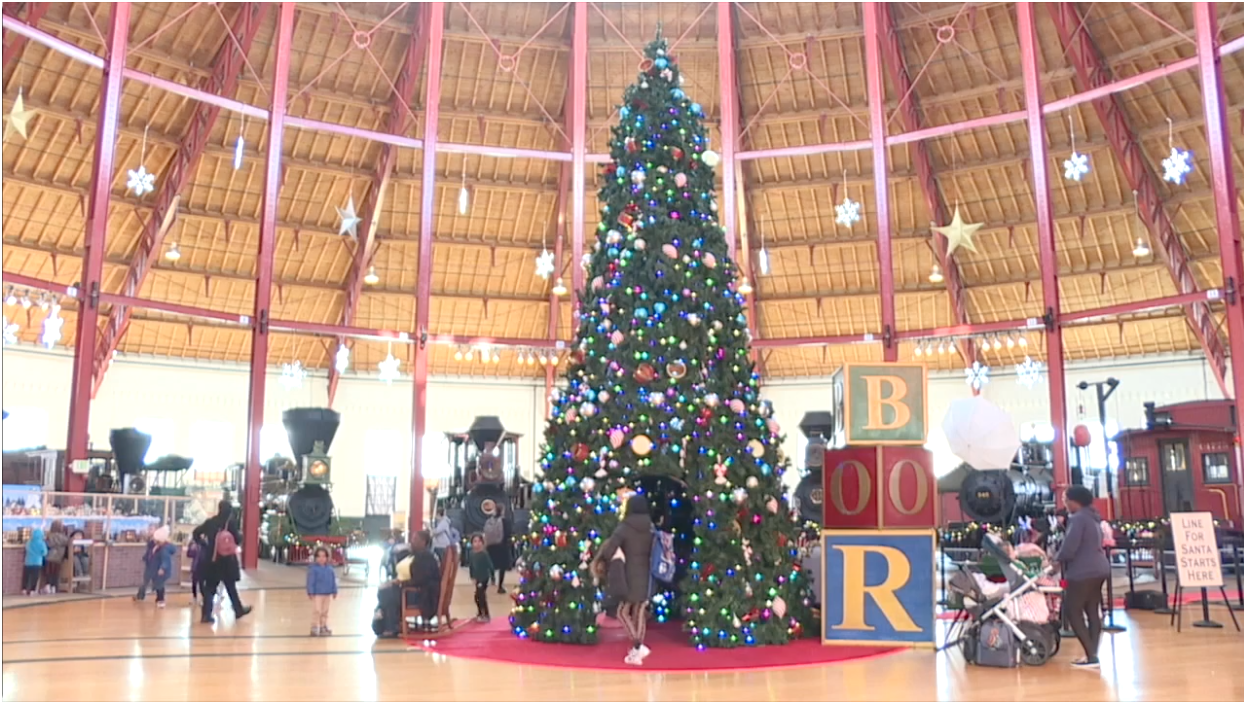 This is an image of a large open space with locomotives on the outer edges and a large Christmas tree in the middle.